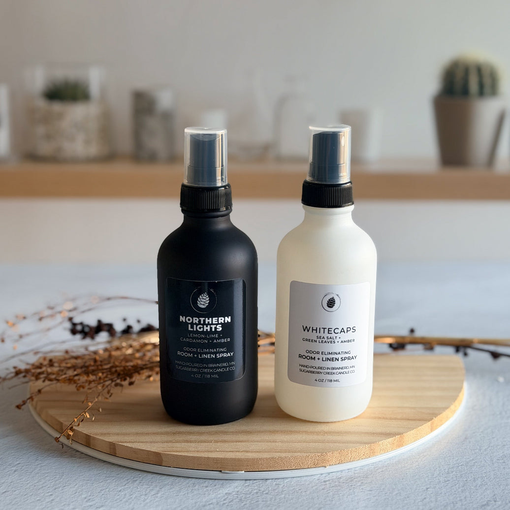 Black and white room spray bottles on a wood tray with dried flowers