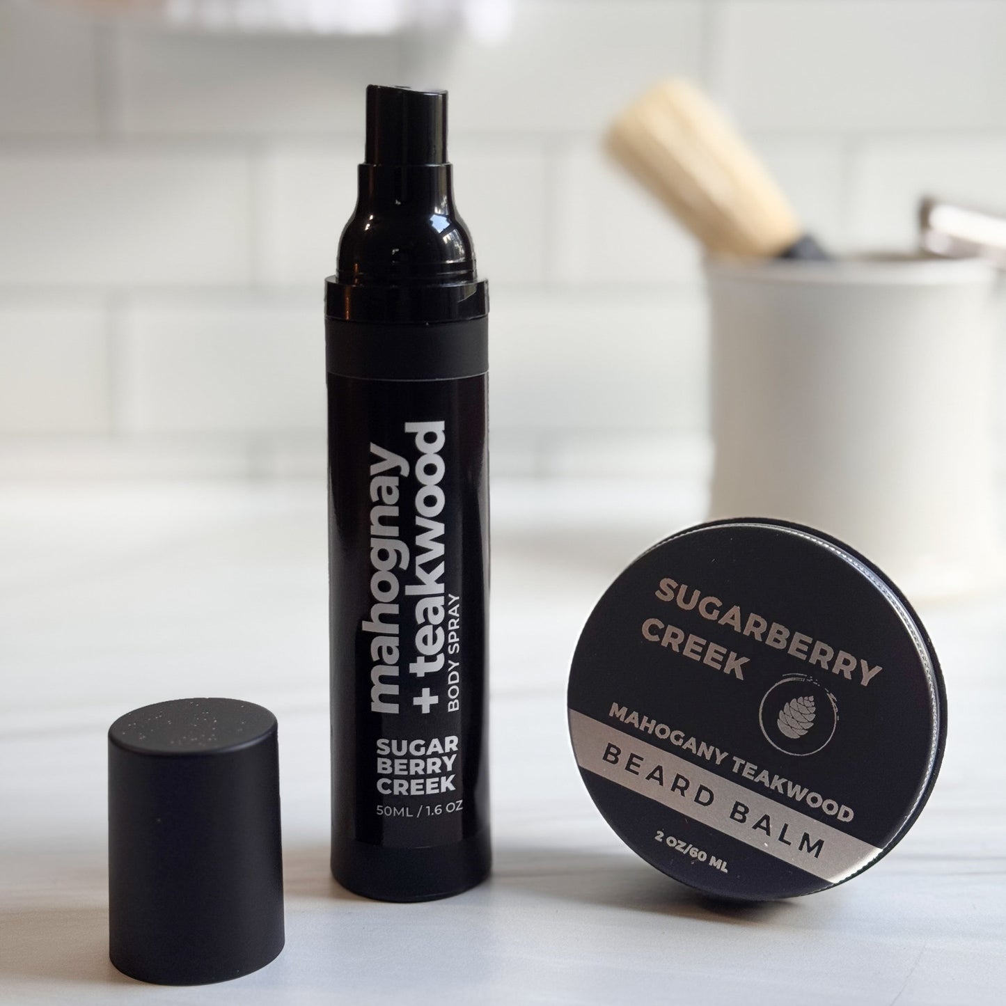 Mahogany + Teakwood body spray and bear balm with in front of a tile background