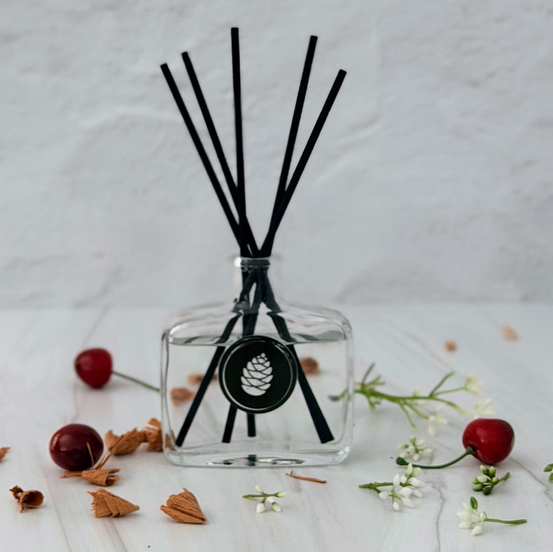 Clear diffuser bottle with black sticks on a light surface with decorative elements