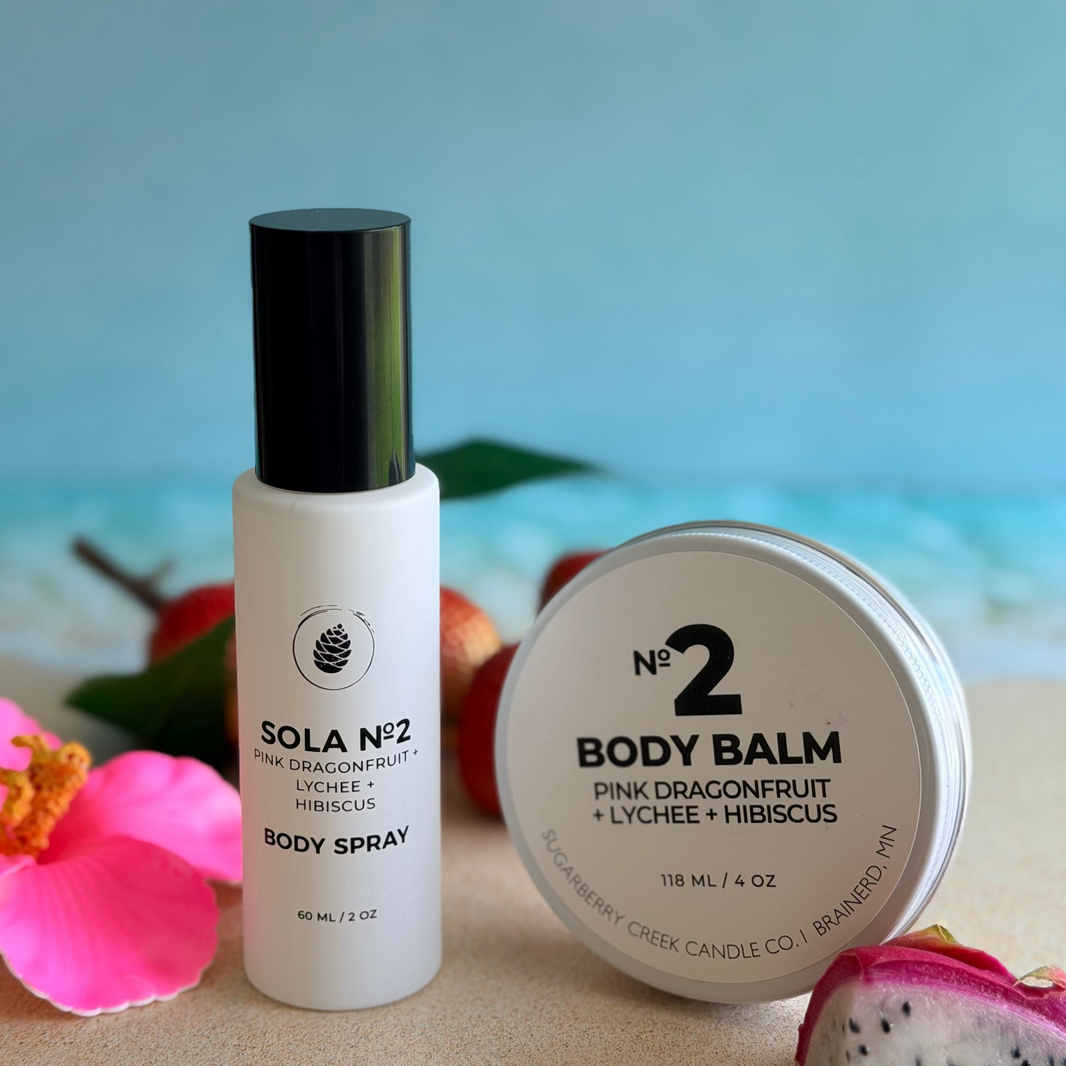 Body spray and balm with dragon fruit and pink flower on a beach background