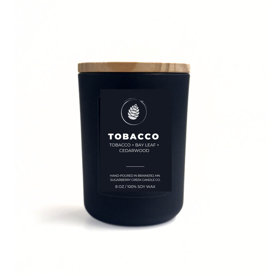 Black candle with a wooden lid labeled 'Tobacco' on a white background