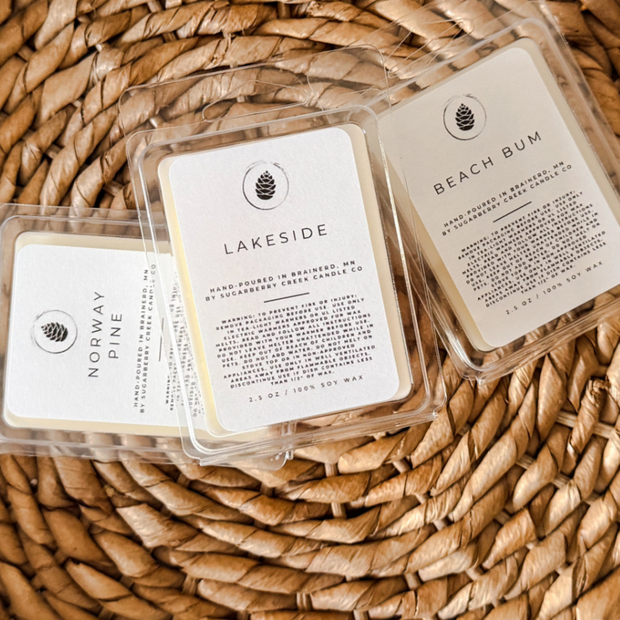 Three small containers labeled 'Lakeside', 'Beach Bum', and 'Norway' on a woven surface.