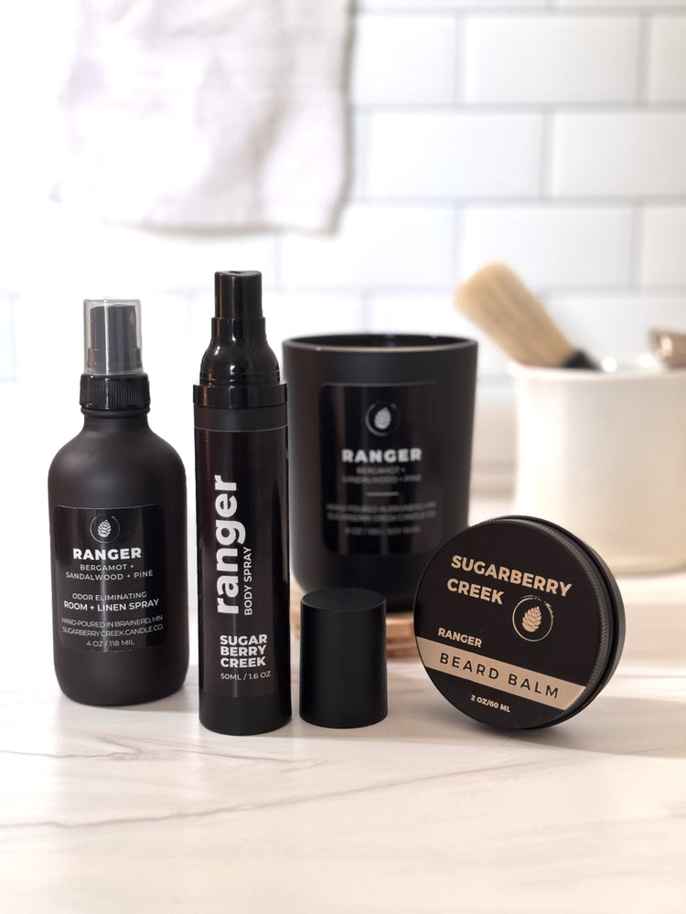 Men's body products, candle and room spray on a marbeled bathroom counter