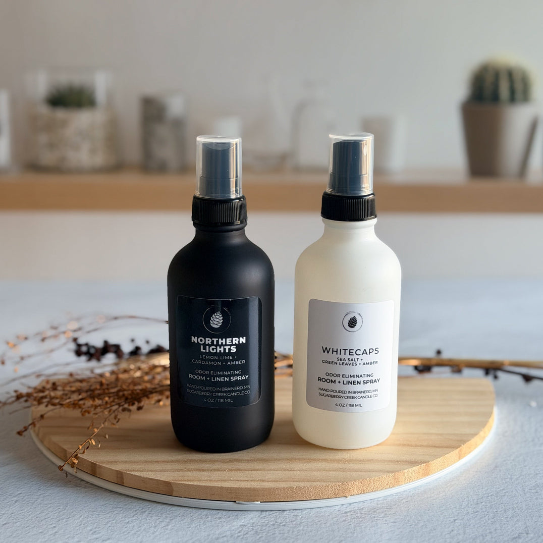 Black and white room spray bottles on a wood tray with dried flowers