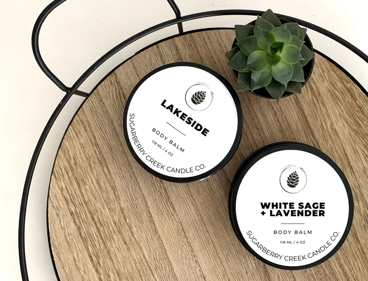 lAKESIDE AND whITE sAGE & AVENDR BODY BALM TINS ON A WOOD TRAY