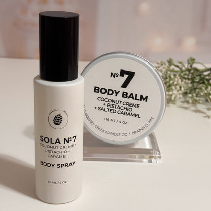 Body spray bottle and body balm on a white surface with a soft blurred background