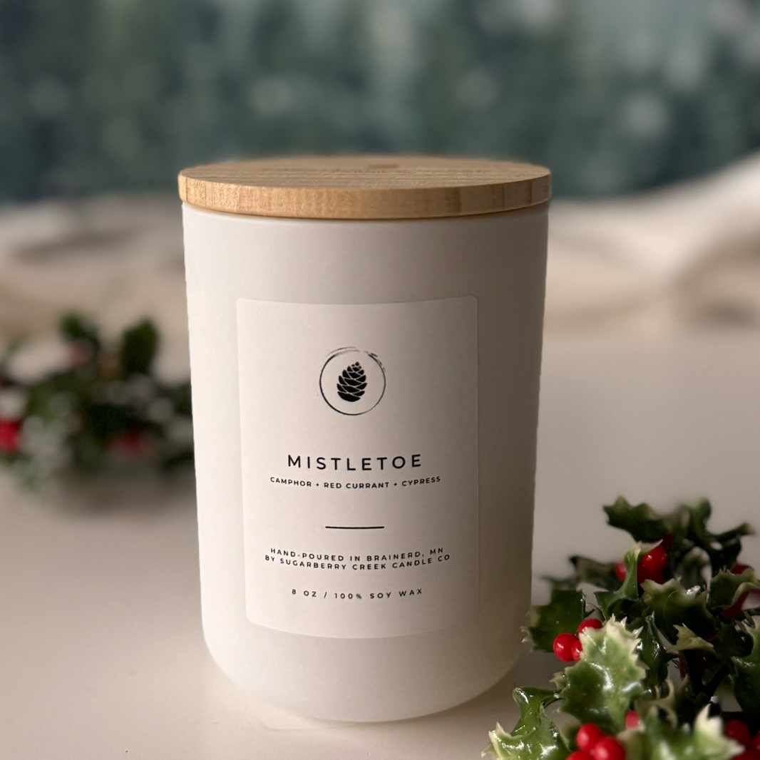 Mistletoe Soy Candle with mistletoe and pine trees in the background.