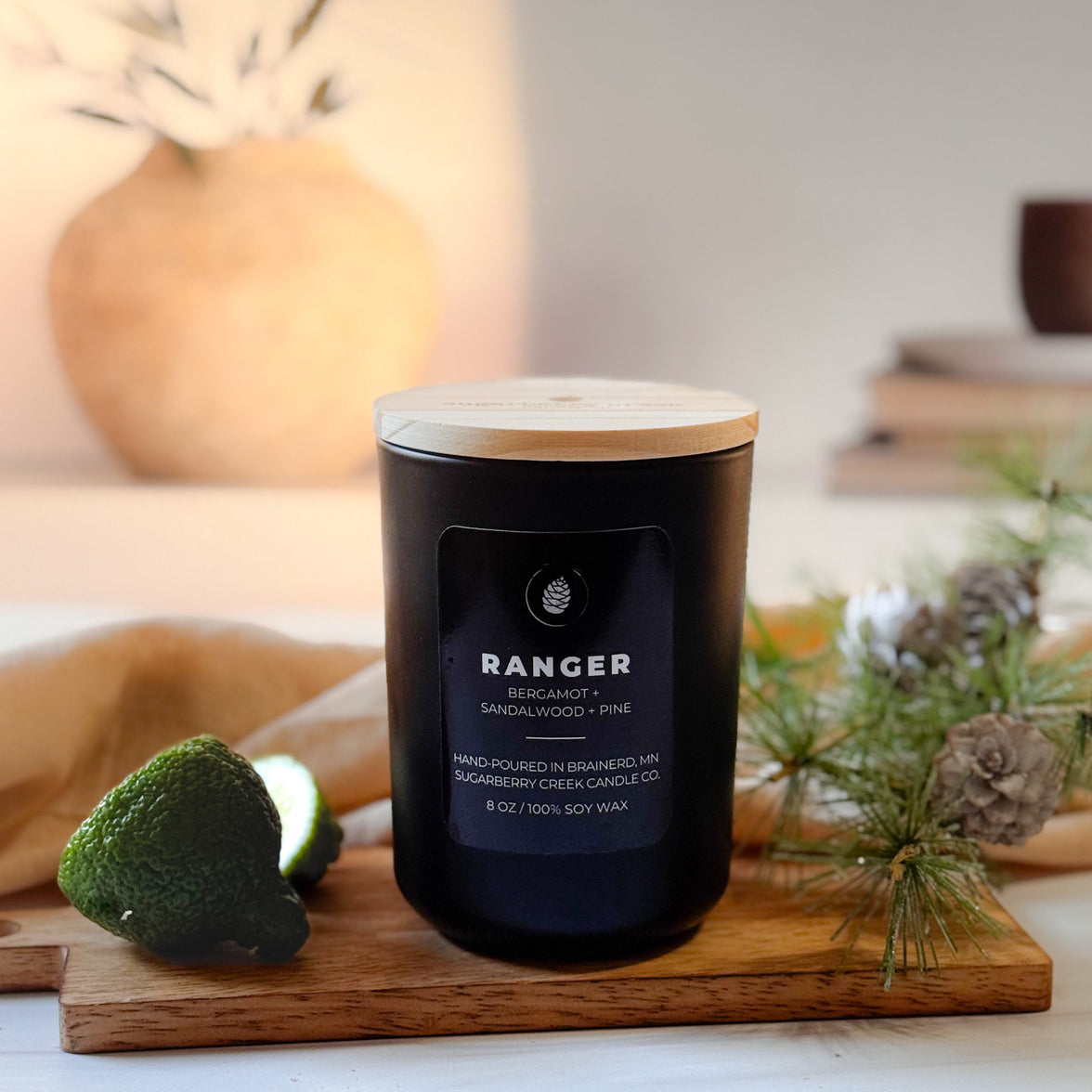 Black candle labeled 'Ranger' on a wooden cutting board with decorative elements in the background.