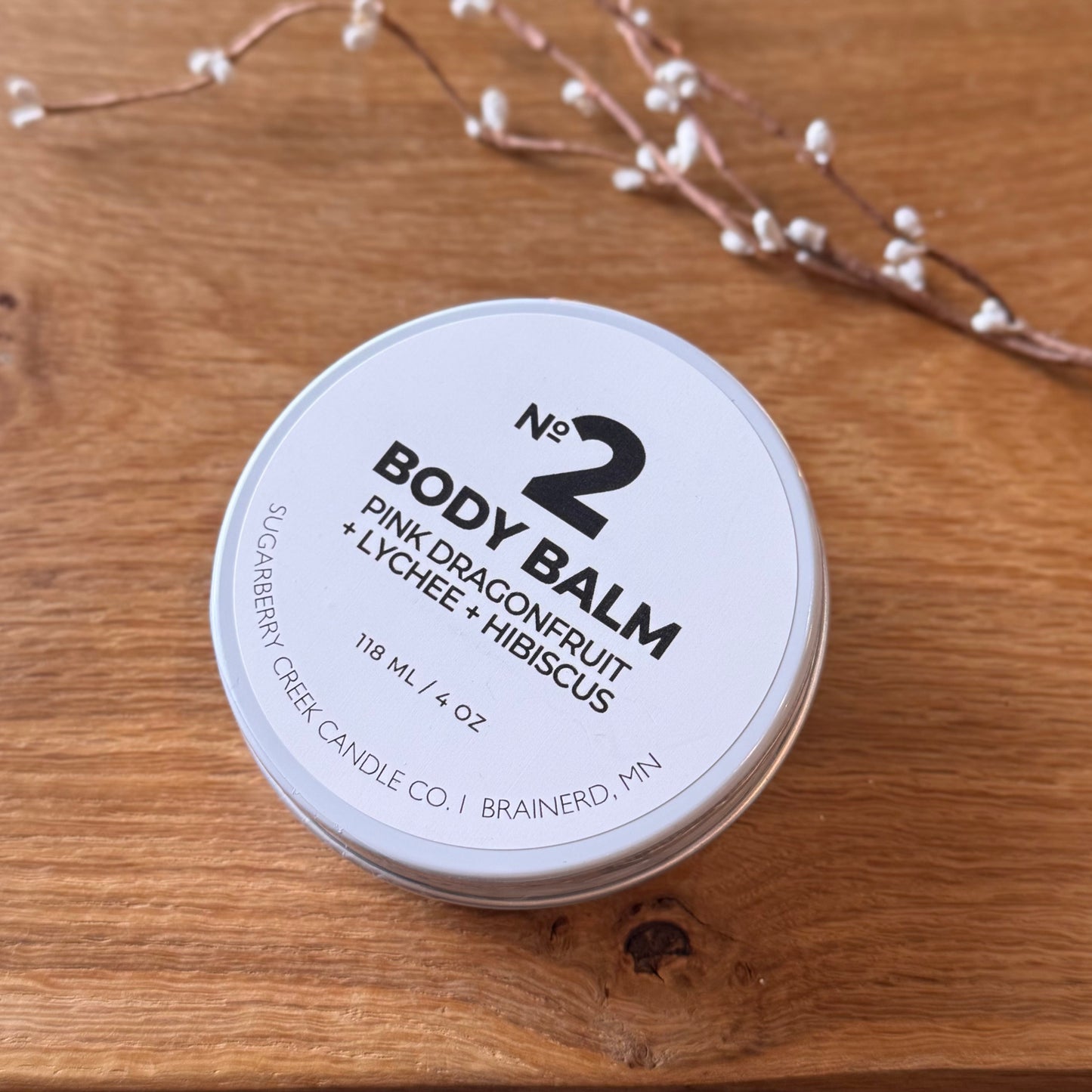 Body balm container labeled 'No. 2' on a wooden surface with decorative elements.