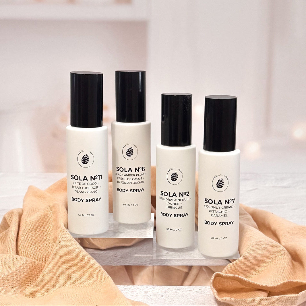 Four bottles of Sola body spray on a white surface with a beige towel.
