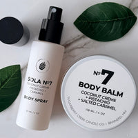 Body spray and body balm with green leaves on a marble surface