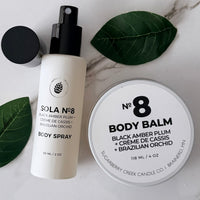 Body spray and body balm with 'Sola No. 8' branding on a marble surface with leaves.