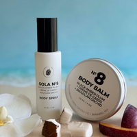 Body spray and balm with ingredients on a textured surface with a blue gradient background