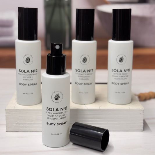 Set of Sola body spray bottles on a white surface with a blurred background