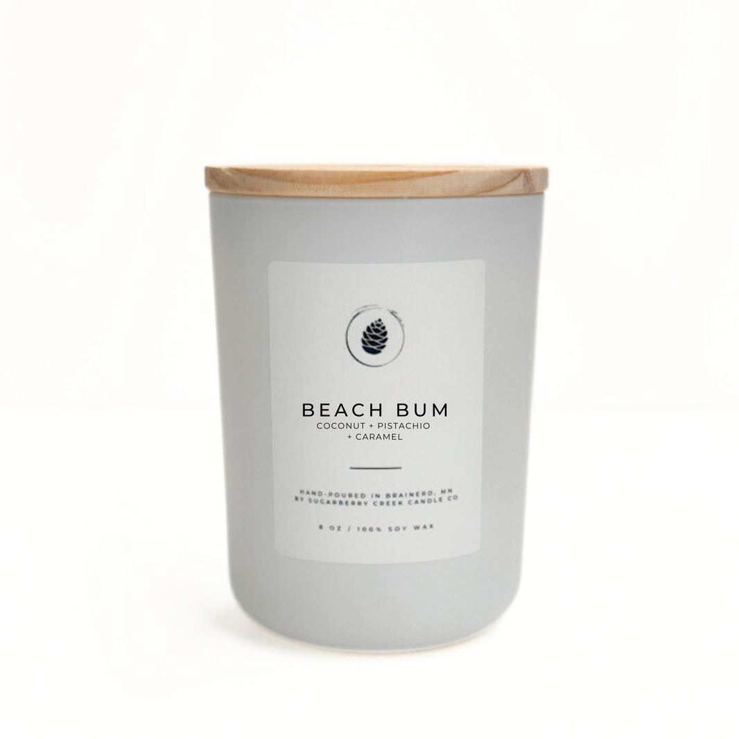 Candle with a wooden lid labeled 'Beach Bum' on a white background