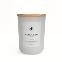 Candle with a wooden lid labeled 'Beach Bum' on a white background