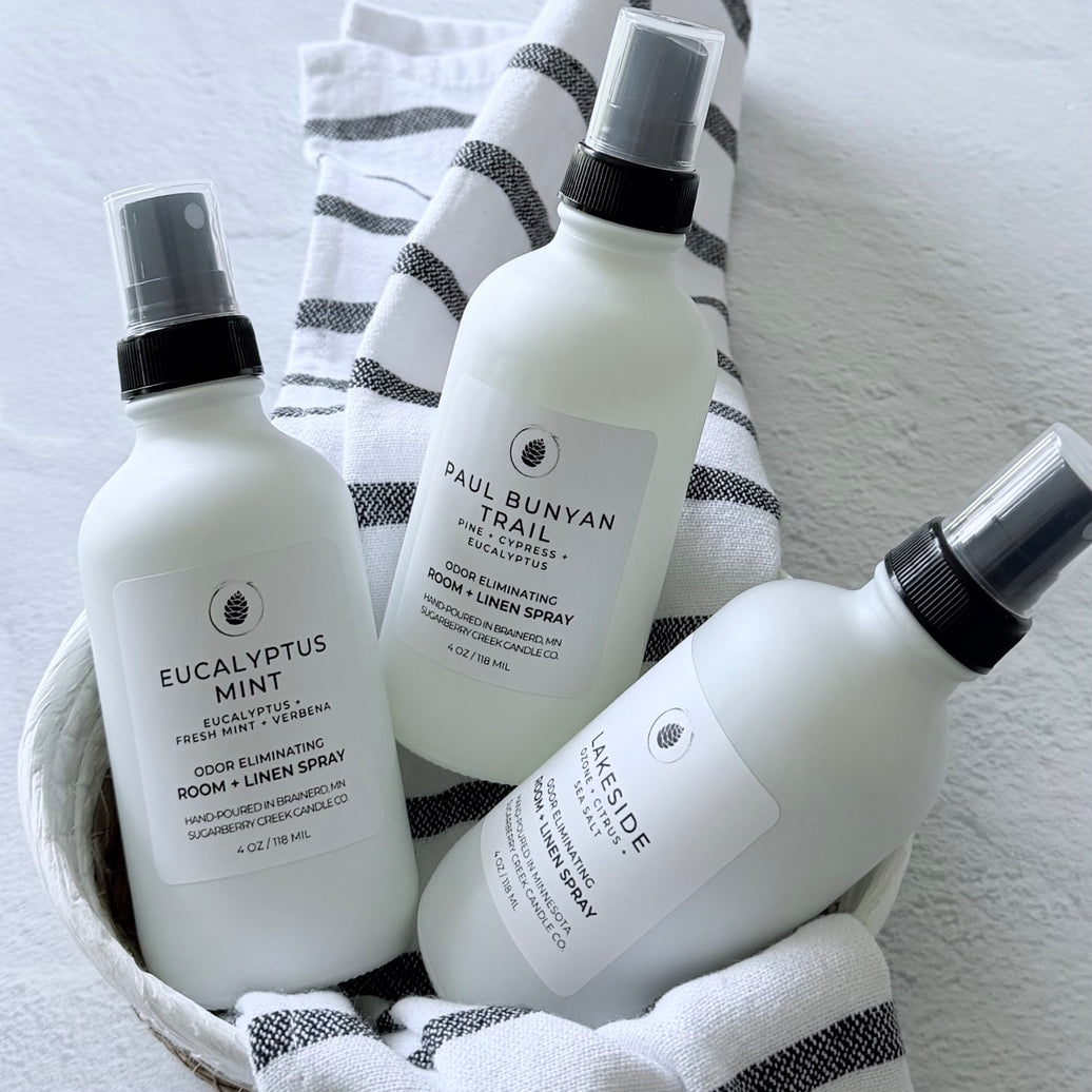 Three white spray bottles with black nozzles on a striped towel.