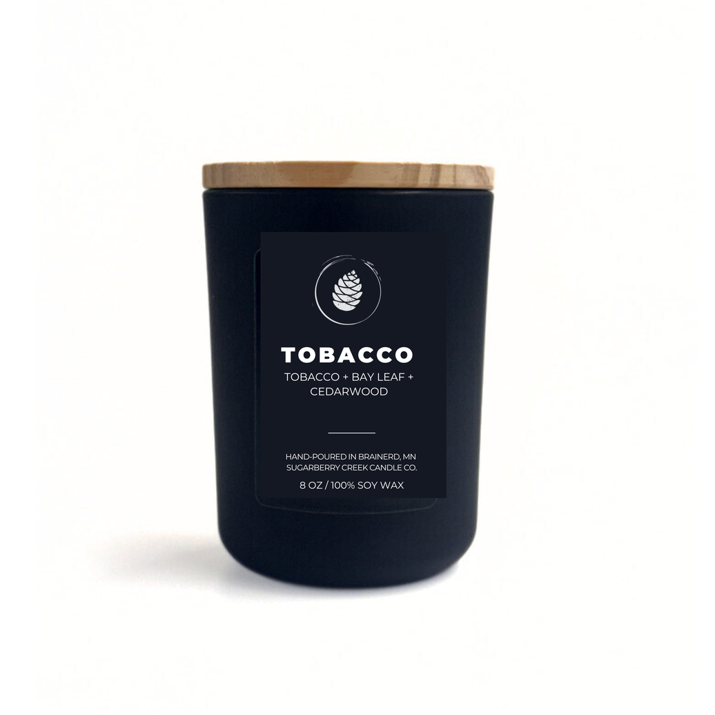Black candle with a wooden lid labeled 'Tobacco' on a white background