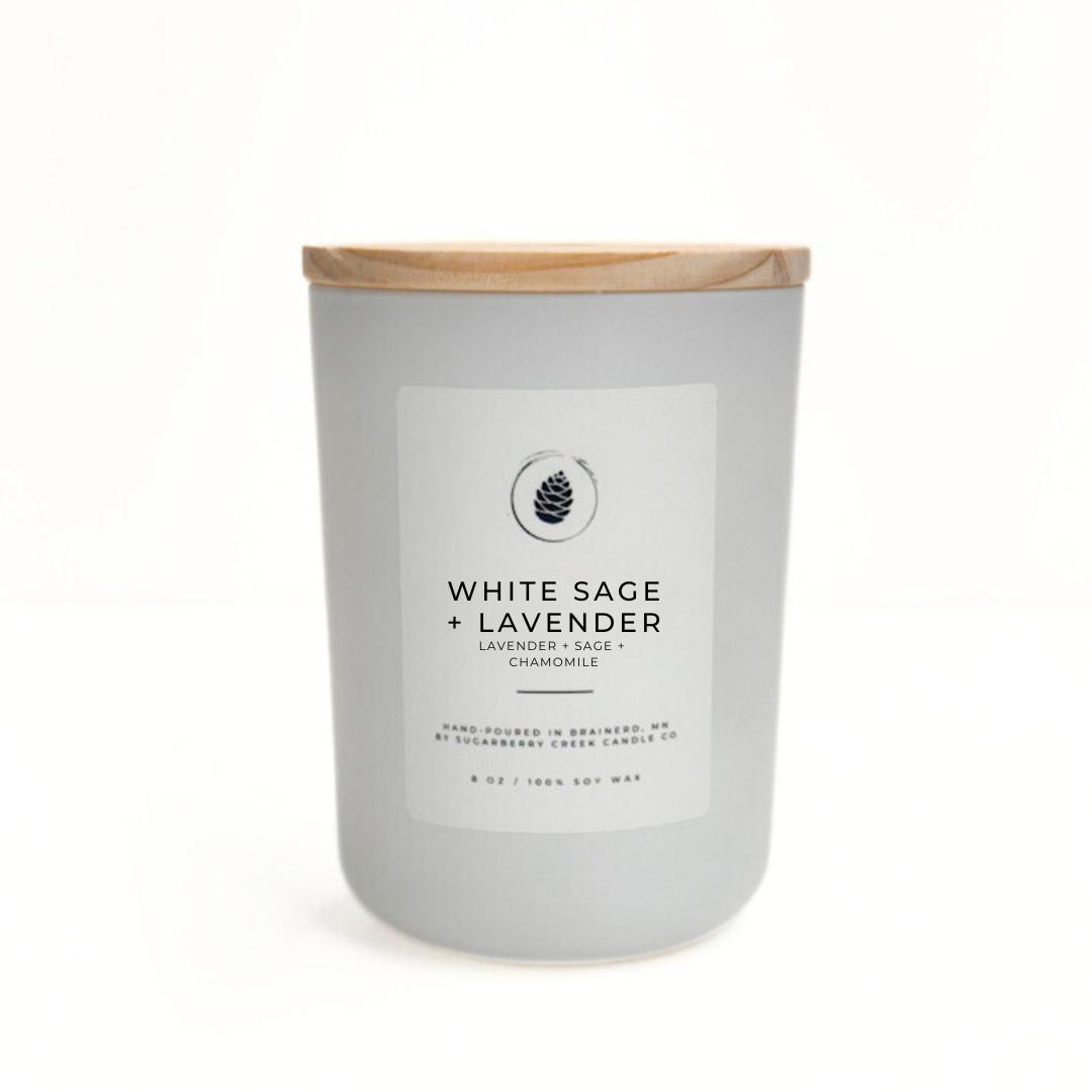 White sage and lavender candle with a wooden lid on a white background